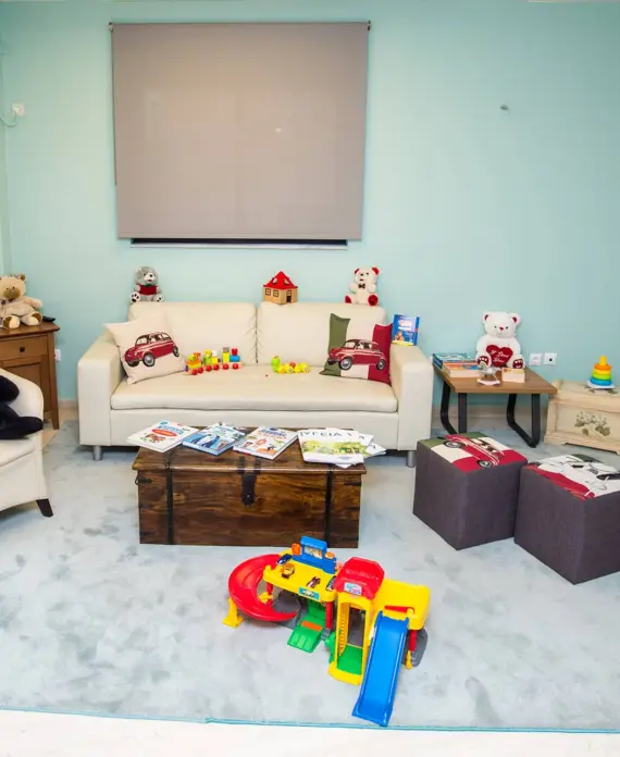 Η παιδίατρος 6 Φιλόξενος παιδικός χώρος υποδοχής με άνετες πολυθρόνες, λούτρινα αρκουδάκια και παιχνίδια, διακοσμημένος σε απαλούς γαλάζιους τόνους